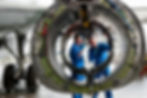 This photo shows two technicians inspecting the substructure of a jet engine that is attached to a commercial aircraft wing.